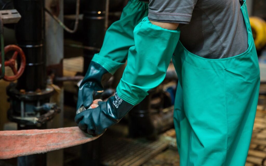 Pracownik w rękawicach chemoodpornych przy zaworze instalacji